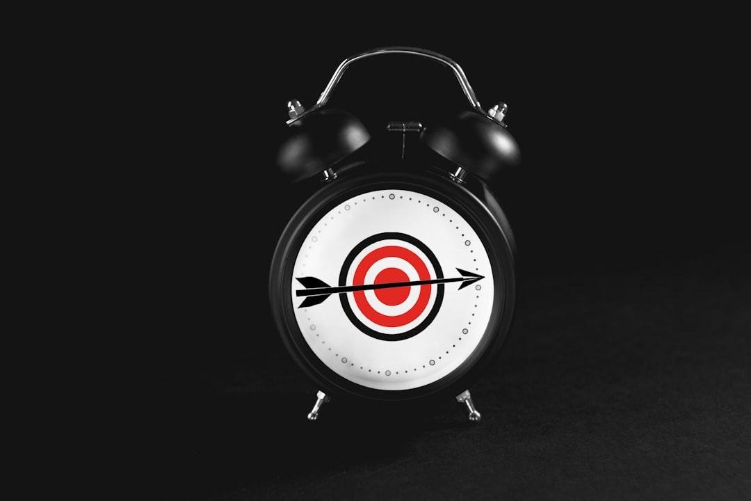 Alarm clock with target and arrow on face.