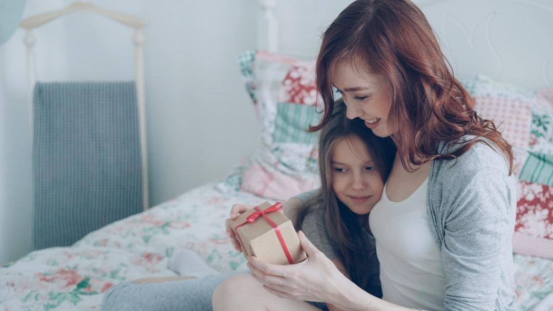 Mother and daughter share a gift on the bed.